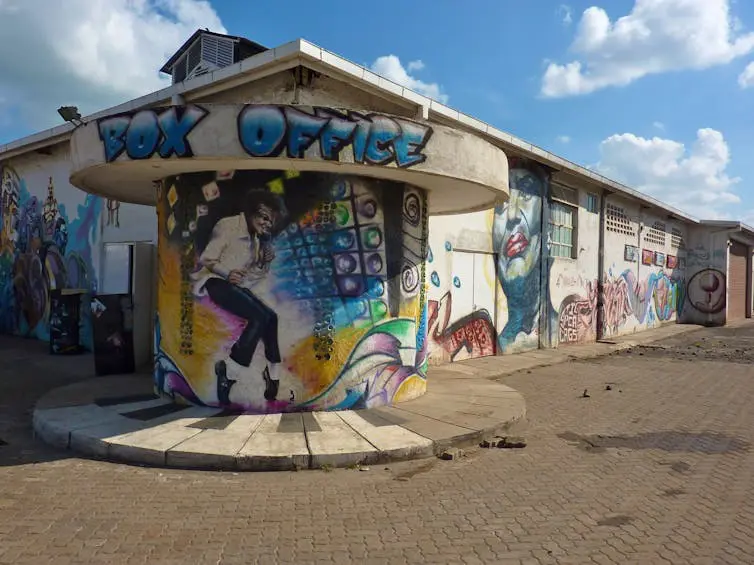 An urban structure with a circular building in front of it. This has been spray painted with the word 